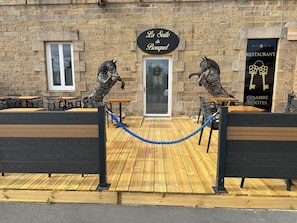 Ein Restaurant namens 'La Suite du Bouquet' mit Außenbestuhlung und zwei Pferdestatuen.