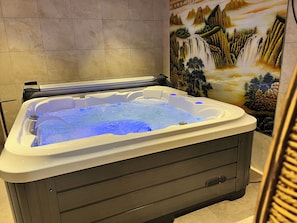 A hot tub with a waterfall mural in the background.