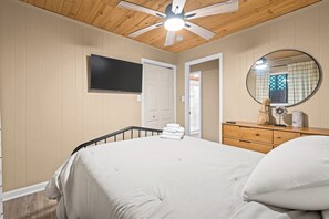 Ein Schlafzimmer mit Bett, Schminktisch, Spiegel und Deckenventilator.