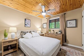 A bedroom with a bed, nightstands, a ceiling fan, and a window with curtains. - Cozy 2BR for 4 w/ BBQ Grill, Mins to Attractions! (Gatlinburg)
