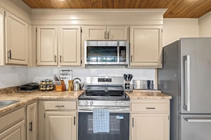 A modern kitchen with stainless steel appliances, including a microwave, oven, and refrigerator. - Cozy 2BR for 4 w/ BBQ Grill, Mins to Attractions! (Gatlinburg)