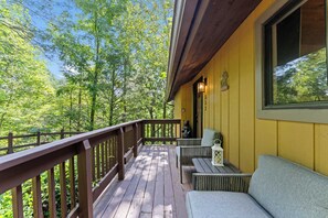 A wooden deck with a railing, a bench, and a table, overlooking a forested area. - Cozy 2BR for 4 w/ BBQ Grill, Mins to Attractions! (Gatlinburg)
