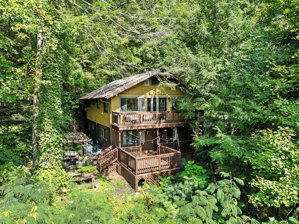 A two-story wooden cabin surrounded by dense forest. - Cozy 2BR for 4 w/ BBQ Grill, Mins to Attractions! (Gatlinburg)