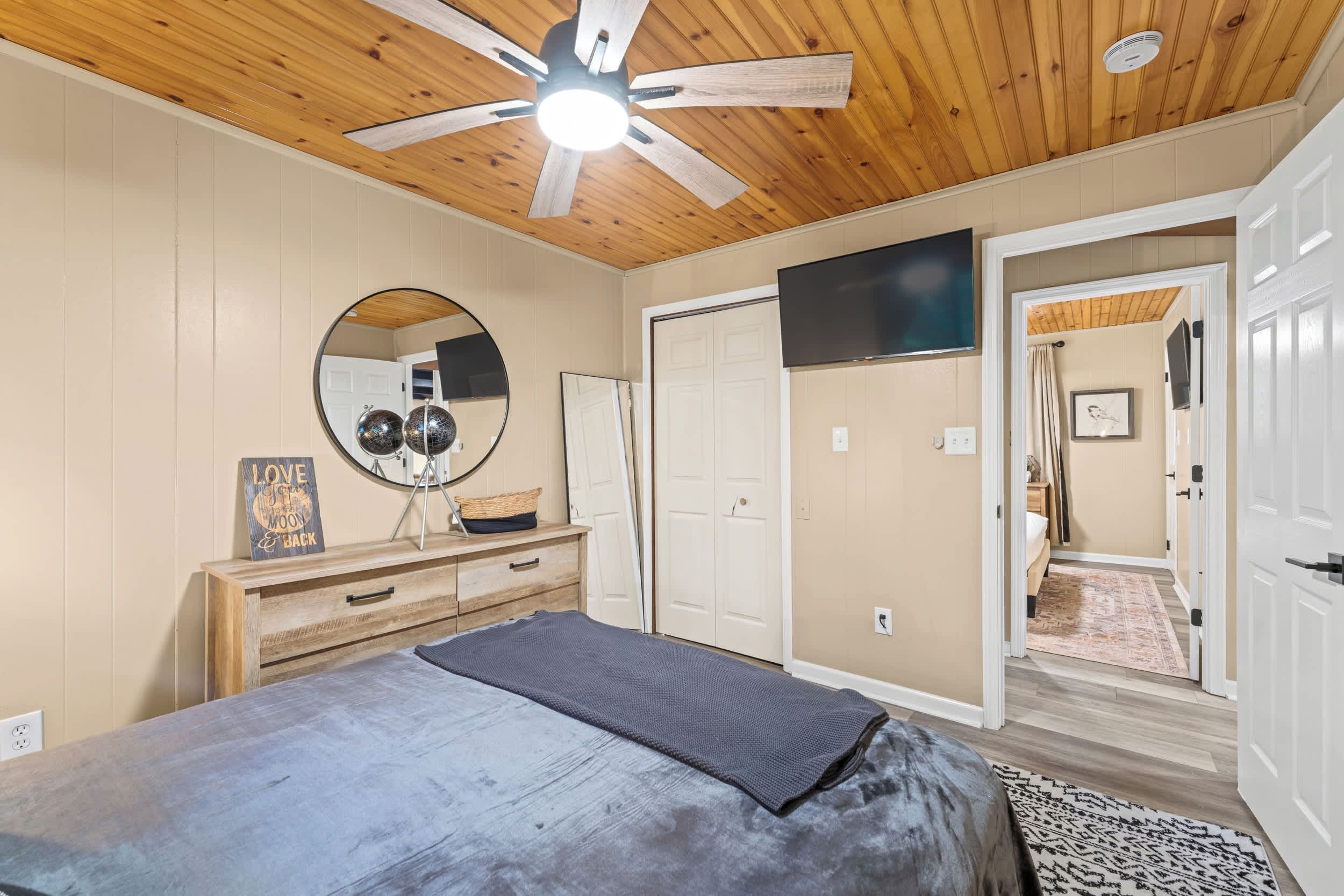Ein Schlafzimmer mit einem Bett, einem Schminktisch, einem Spiegel und einem Deckenventilator.
