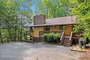 Eine gelbe Holzhütte mit einem Metalldach, einer Holzterrasse und einer Treppe, die zu einer Veranda führt.
