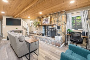 Ein gemütliches Wohnzimmer mit Kamin aus Stein, einem flachbildfernseher an der Wand und einer komfortablen Sitzecke mit Sofas und Couchtisch.
