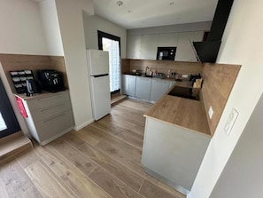 A modern kitchen with a built-in oven, a coffee machine, and a dishwasher. - L Écrin Ludovicien (SAINT LOUIS)