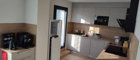 A compact kitchen with a refrigerator, microwave, and coffee machine.