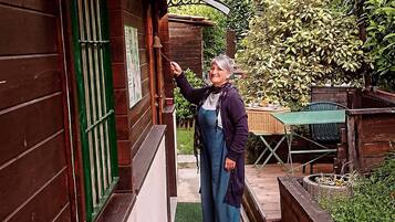 Eine Person steht vor einer Holztür mit einem grünen Fenster, einer Klingel und einem Schild, auf dem 'FISCHIA' steht, im Hintergrund.