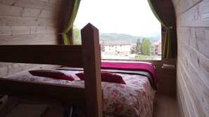 Ein hölzernes Etagenbett mit floralem Bettzeug und einem roten Kissen.