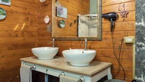 A wooden-paneled bathroom with two white sinks, a mirror, and a hairdryer on the wall. - Vrbo Property (Murazzano)