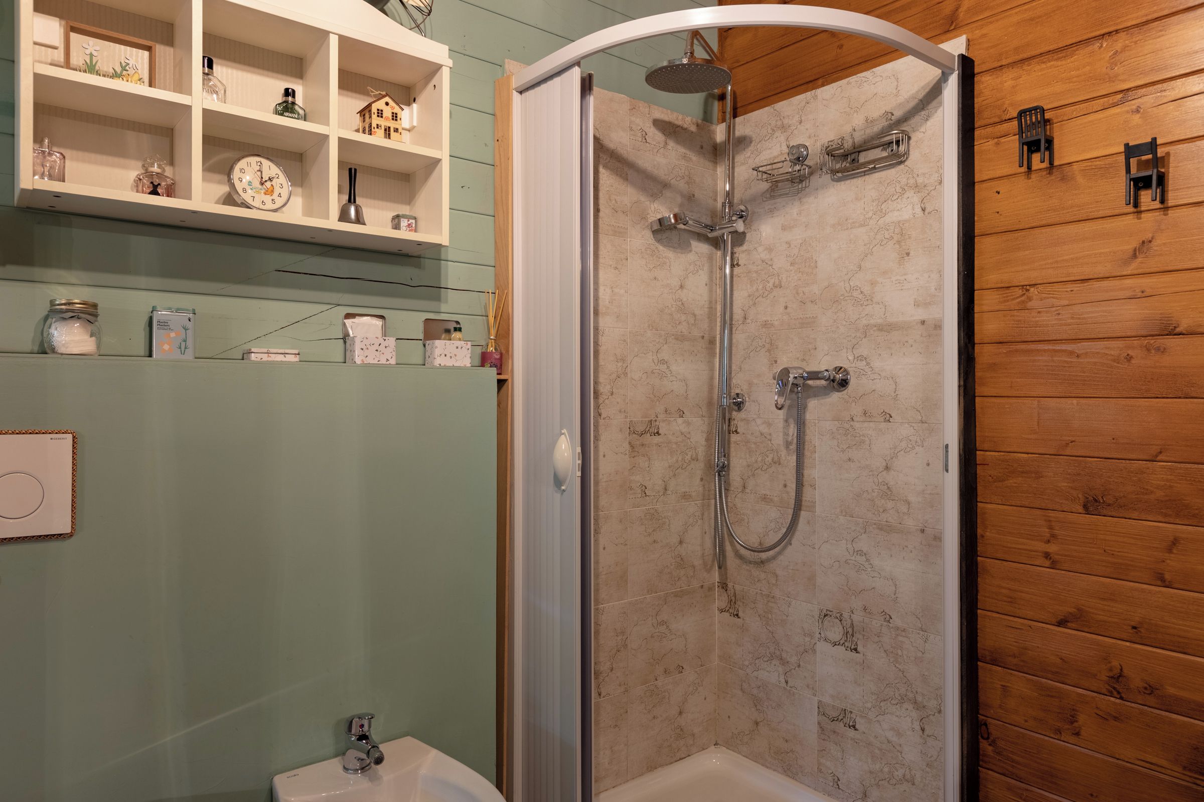 A bathroom with a shower, a sink, and a shelf with toiletries.