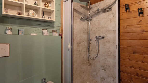 A bathroom with a shower, a sink, and a shelf with toiletries. - Vrbo Property (Murazzano)