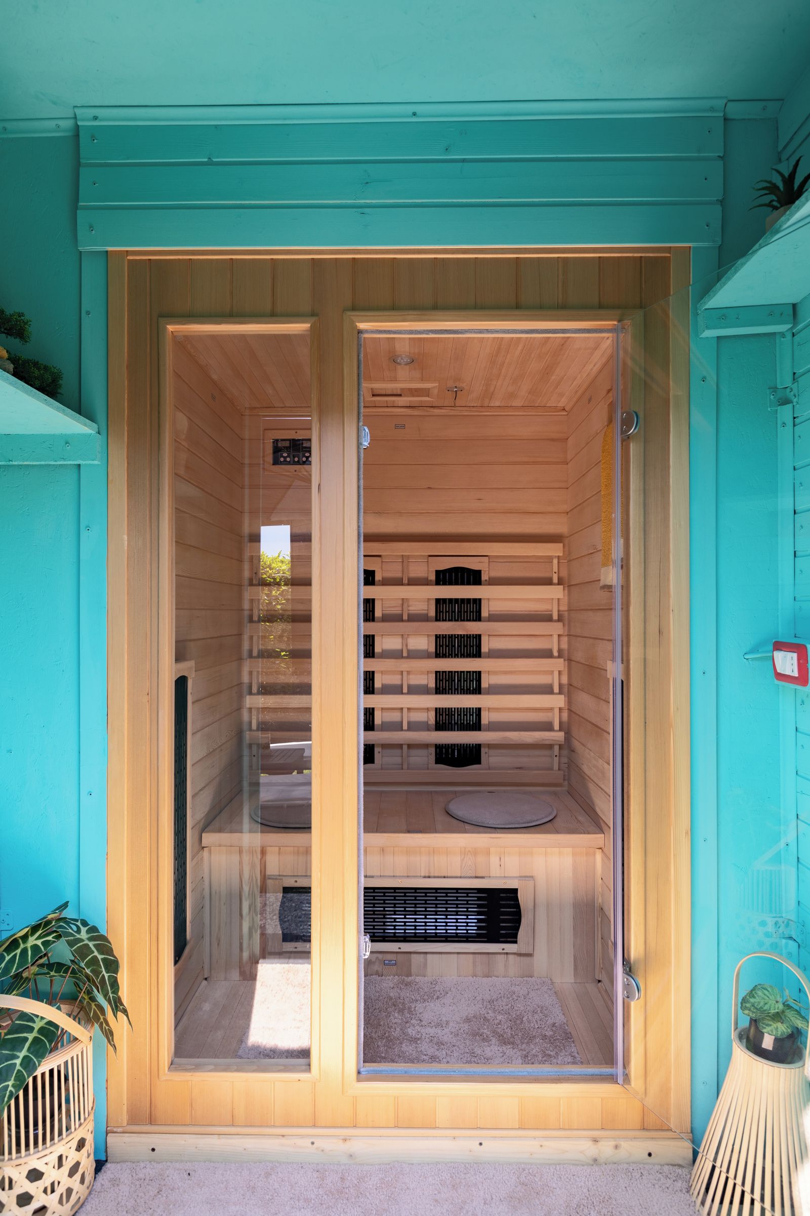 Uma sauna com interior de madeira, portas de vidro e uma pequena janela.