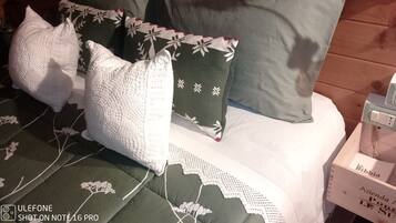 A bed with multiple pillows and a bedside table with a power outlet.