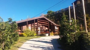 Una cabana de fusta amb un camí de grava que hi convergeix, envoltada de verdura.