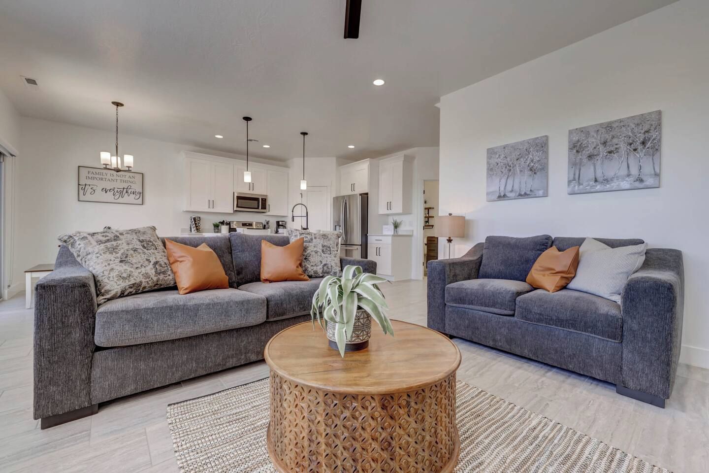 A modern living room with two grey sofas, a wooden coffee table, and a kitchen in the background.