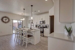 A modern kitchen with white cabinetry, a central island with bar stools, stainless steel appliances, and pendant lighting. - Meticulous & Upscale, Sleeps 10, Private Hot Tub - Perfect Location (Washington)