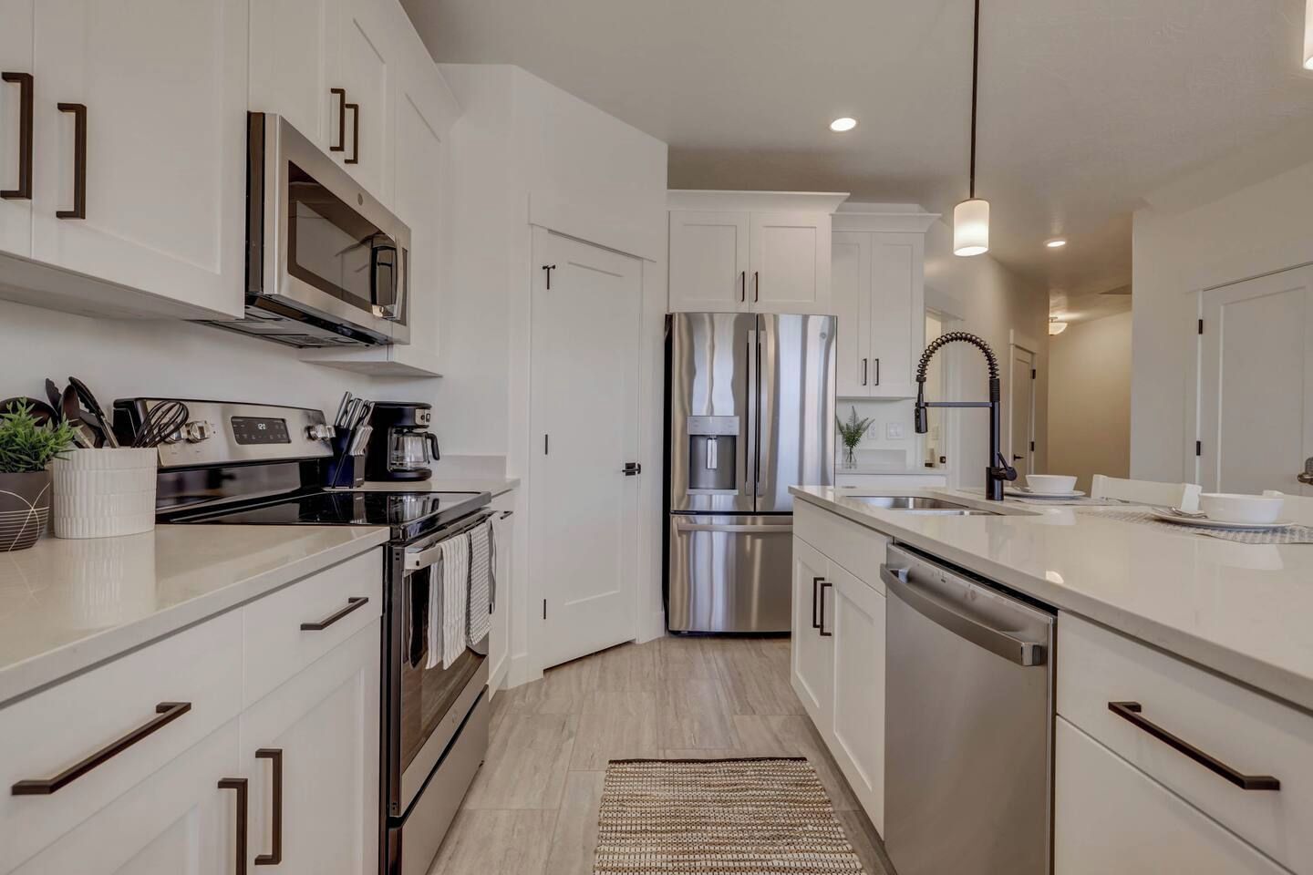 A modern kitchen with stainless steel appliances, white cabinetry, and a central island with a sink.