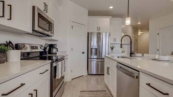 A modern kitchen with stainless steel appliances, white cabinetry, and a central island with a sink.
