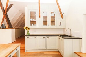 A kitchen with white cabinetry, a black countertop, and a wooden ceiling. - The Hayloft at Manaton (Newton Abbot)