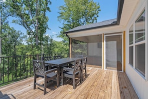 Um terraço com mesa e cadeiras, com vista para uma área arborizada.