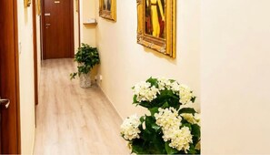 A hallway with a wooden floor, a potted plant, and a framed picture on the wall. - Lumora B&B - Levante Double Room with Balcony, Wi-Fi & Air Conditioning (Crotone)