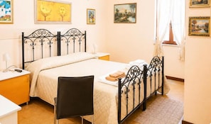 Una camera da letto con un letto, comodini, una sedia e opere d'arte alle pareti.