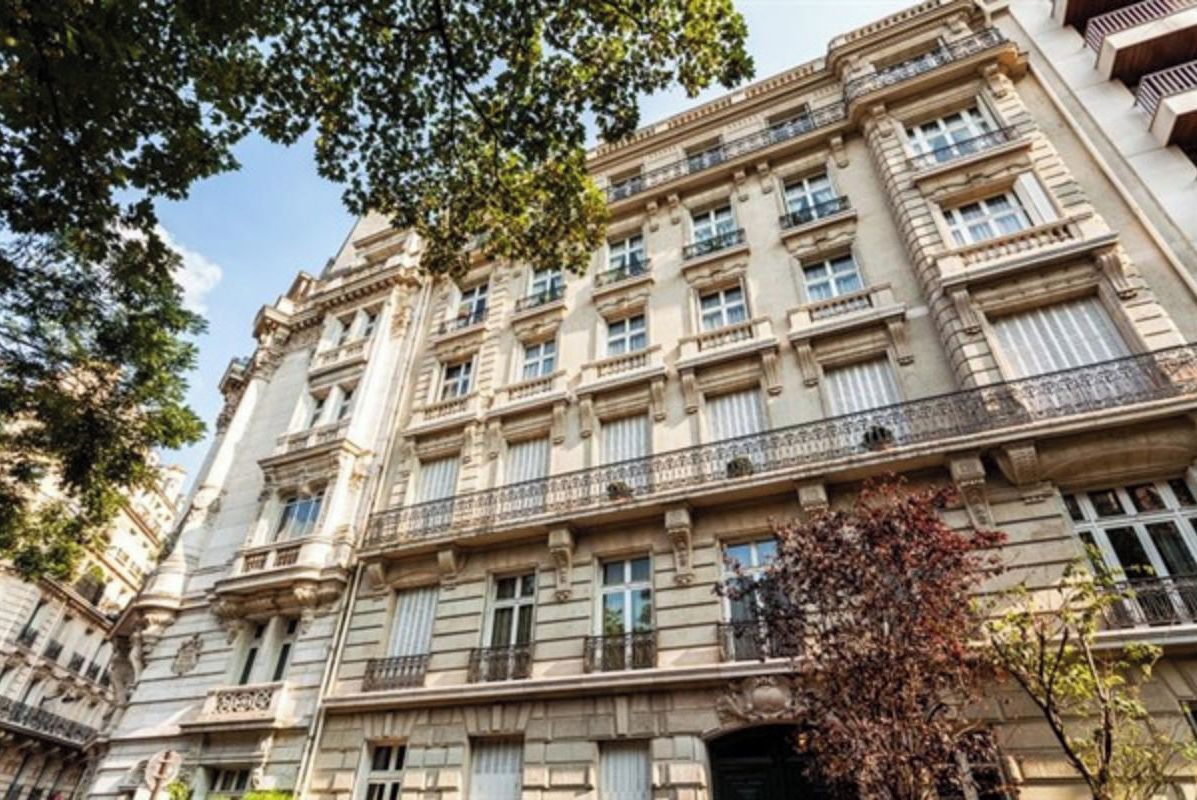 Um edifício de vários andares com arquitetura clássica, com várias janelas e varandas.