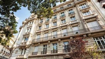 Um edifício de vários andares com arquitetura clássica, com várias janelas e varandas.
