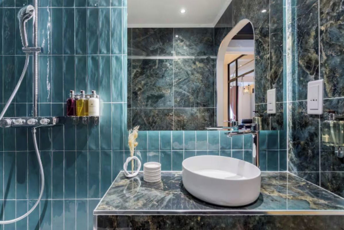 Ein Badezimmer mit Marmorwaschbecken, Dusche und Spiegel.