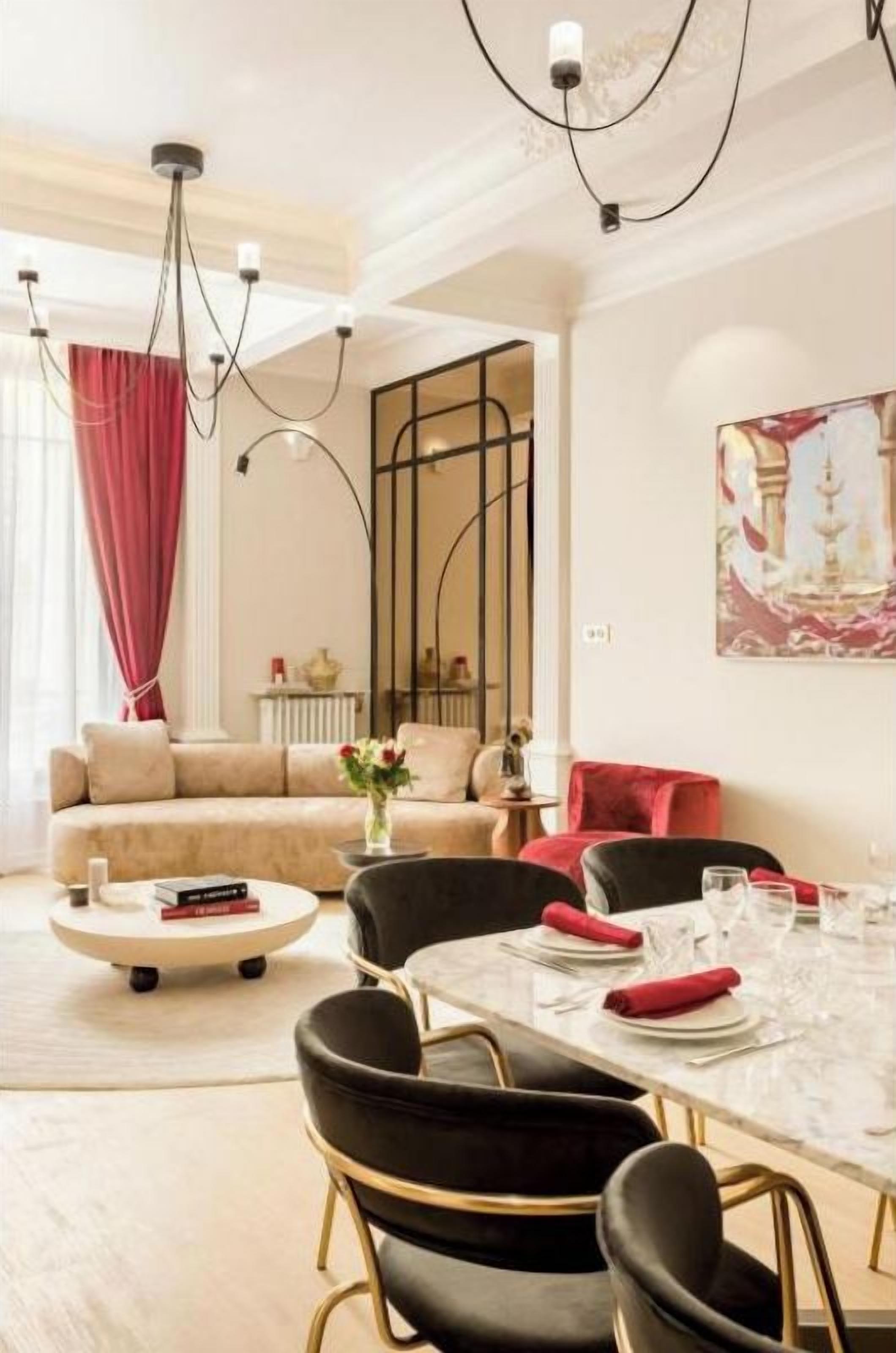 Uma área de refeições com mesa posta para quatro pessoas, um sofá ao fundo e um quadro na parede.