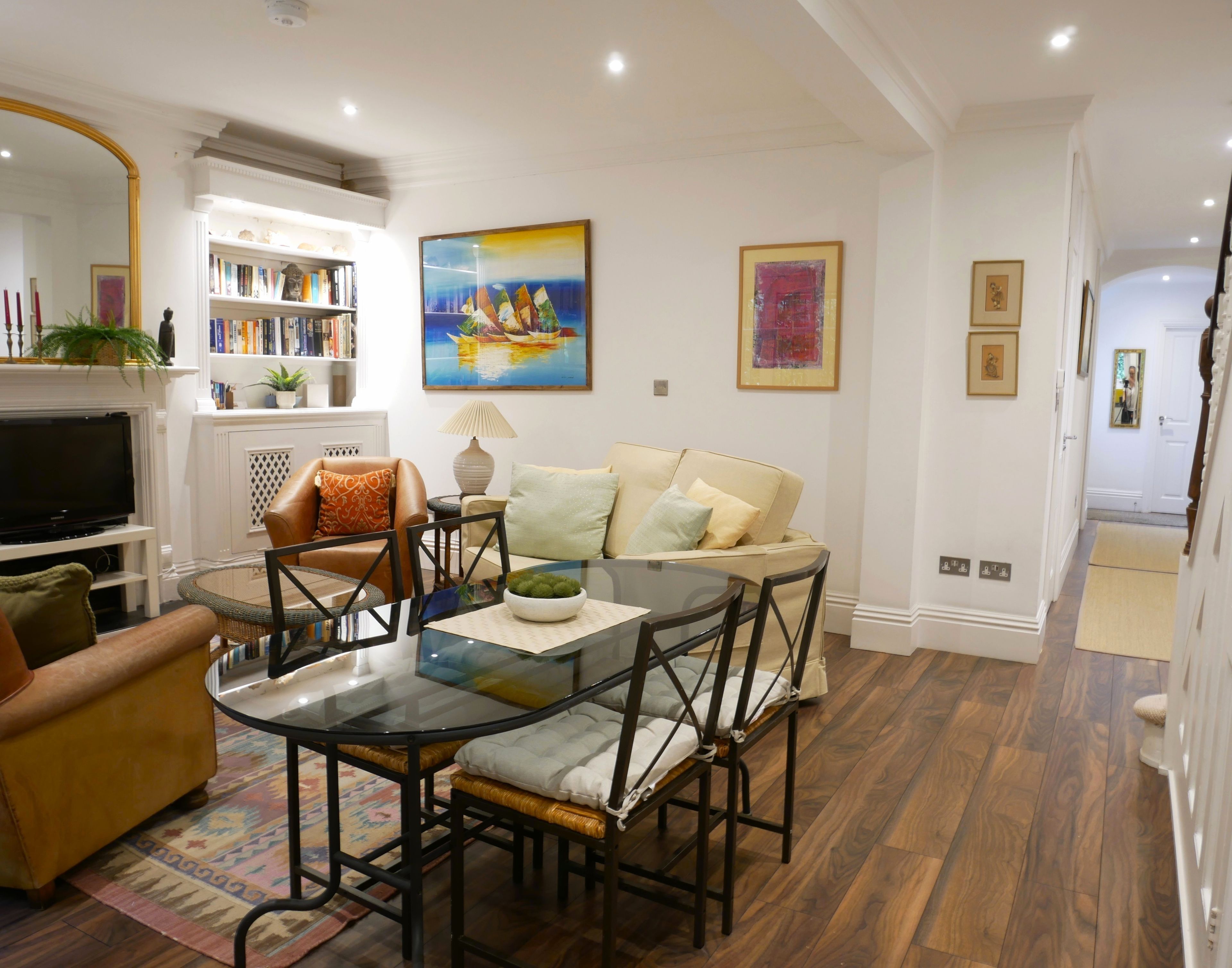 A living room with a glass coffee table, leather sofa, and a fireplace.