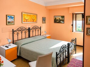 A bedroom with a bed, bedside tables, a chair, and artwork on the walls. - Lumora B&B – Double Room Luce with Wi-Fi and Air Conditioning (Crotone)