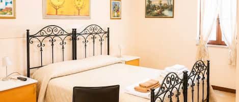 A hotel room with a bed, bedside tables, a chair, and artwork on the walls.