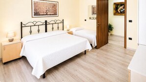 Habitación de hotel con dos camas, suelo de madera y obras de arte en las paredes.