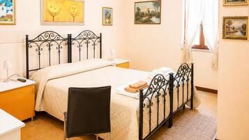 Un dormitorio con cama, mesitas de noche, una silla y obras de arte en las paredes.