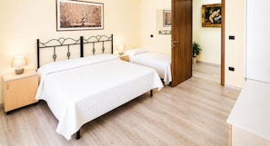 Habitació d'hotel amb dos llits, un sòl de fusta i una porta que dóna a una altra habitació.