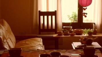 Una habitación con una cama, una mesa con tazas y platos, una silla y una ventana con cortinas.