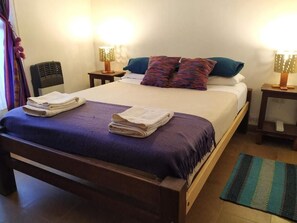 A neatly made bed with folded towels, two bedside lamps, and a small table with a lamp.