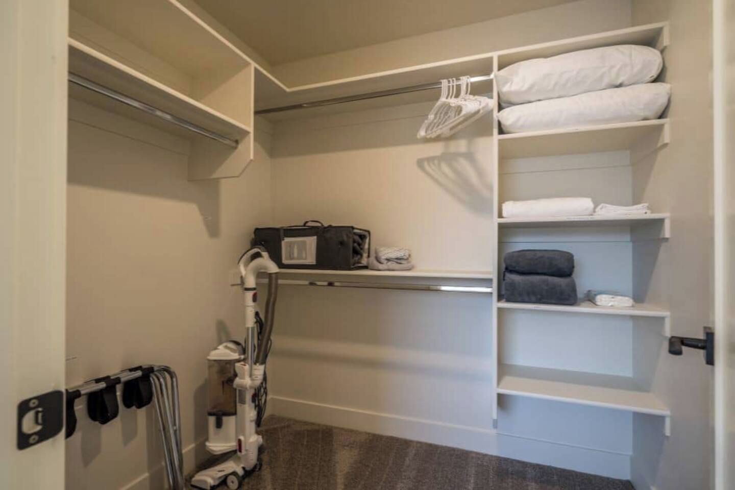 Un vestidor amplio con estantes, una percha para colgar ropa y una aspiradora.