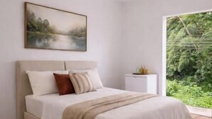 A bedroom with a bed, a ceiling fan, a nightstand, and a window with a view of greenery. - Pousada M&M (Petrópolis)