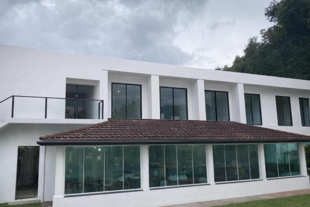 A modern building with a flat roof, large windows, and a balcony.