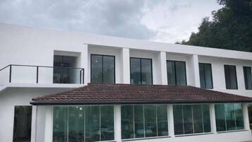 A modern building with a flat roof, large windows, and a balcony.