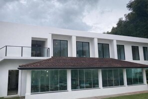 A modern building with a flat roof, large windows, and a balcony.