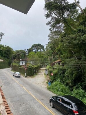A road with cars, surrounded by greenery and houses.
