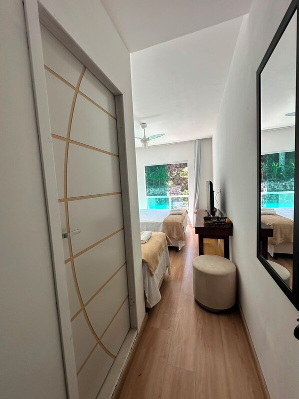 Habitación de hotel con un espejo grande, dos camas, una zona de estar pequeña y vistas a una piscina.