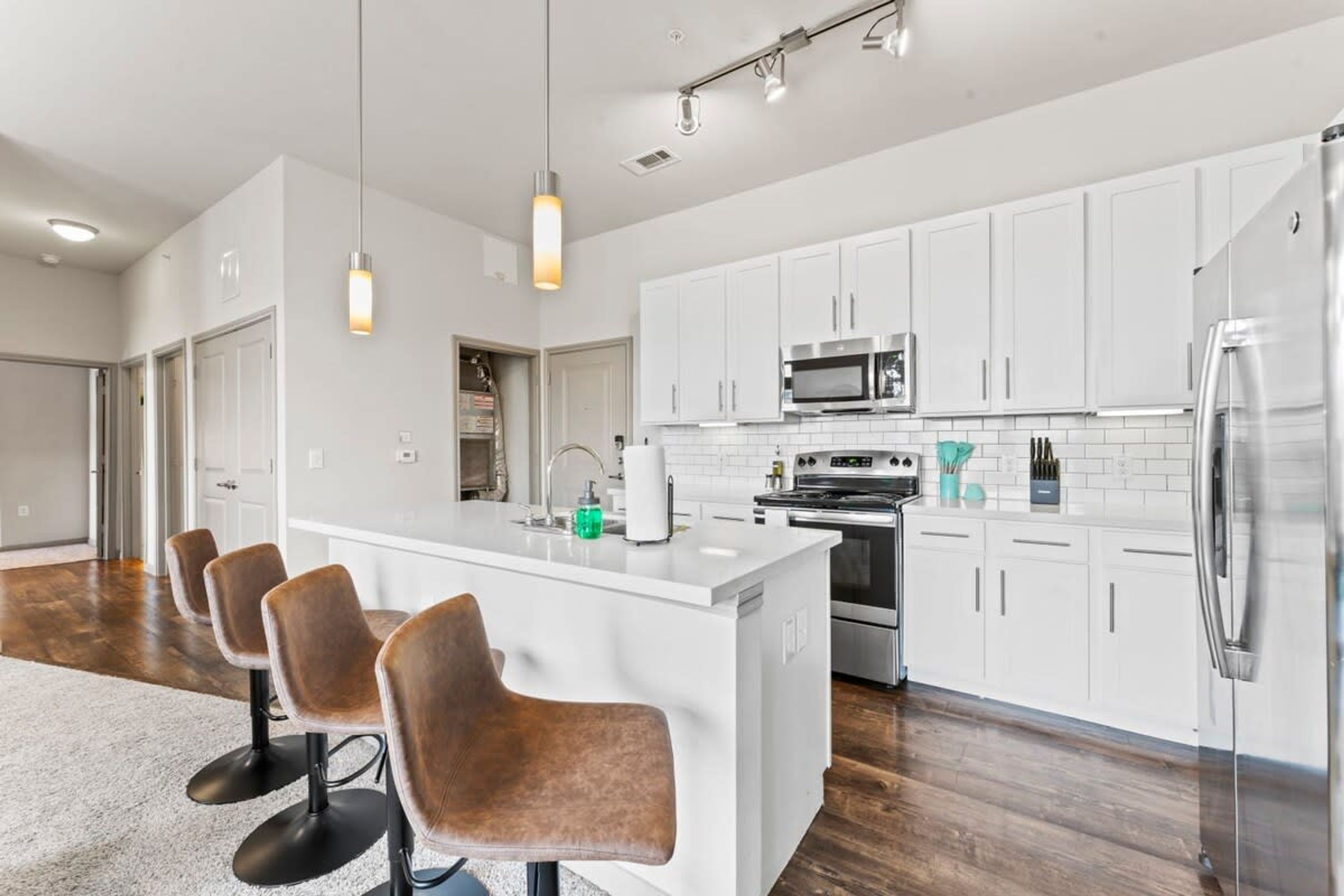 A modern kitchen with white cabinets, stainless steel appliances, and a central island with bar stools.
