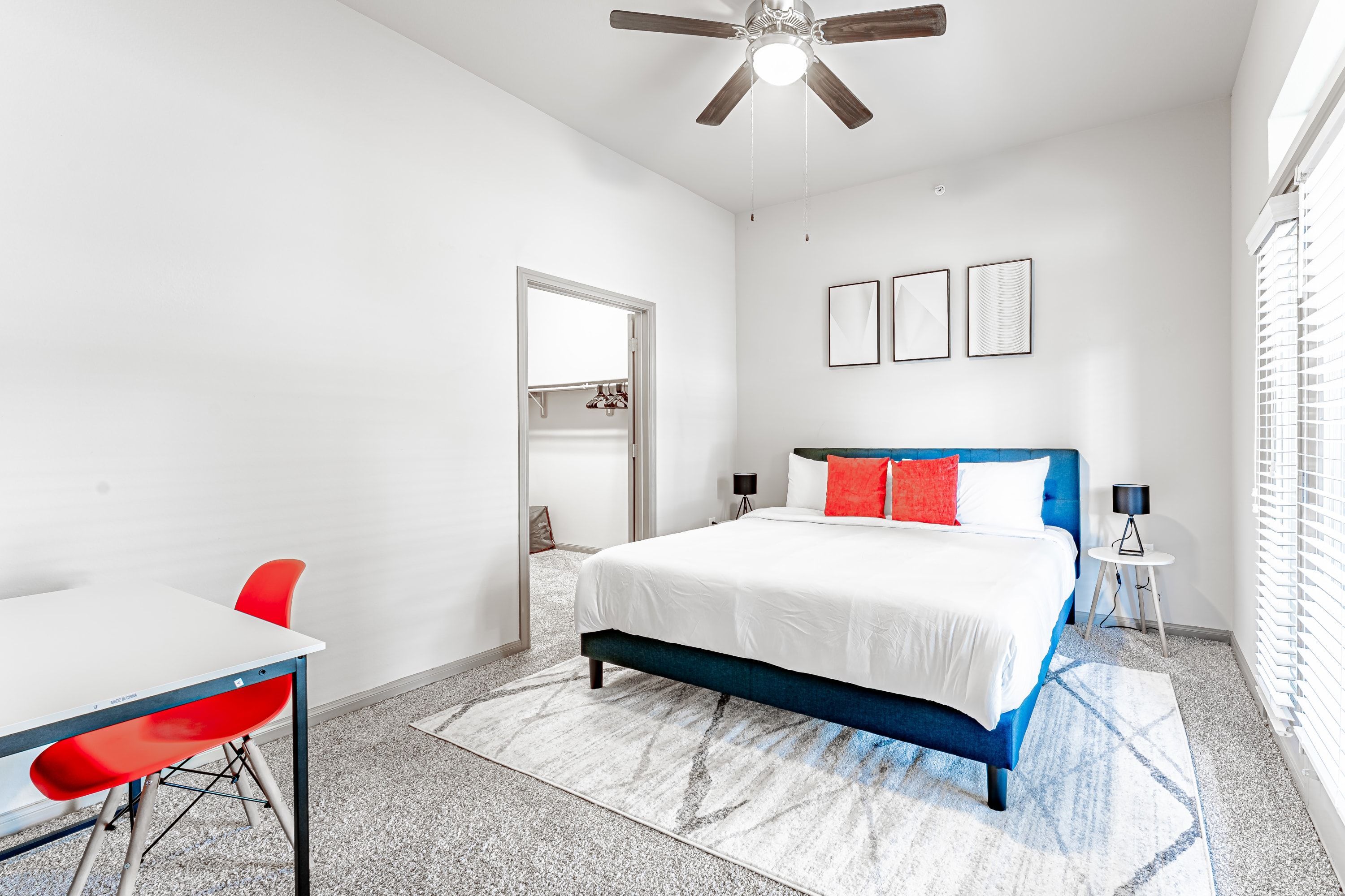 Un dormitorio con cama, escritorio, silla y ventilador de techo.