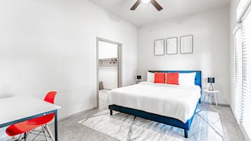 Un dormitorio con cama, escritorio, silla y ventilador de techo.